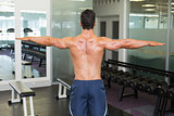 Bodybuilder with arms outstretched in gym