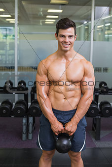 Muscular man lifting kettle bell in gym