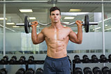 Shirtless muscular man lifting barbell in gym