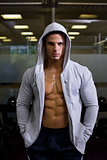 Portrait of a muscular man in hood jacket at gym