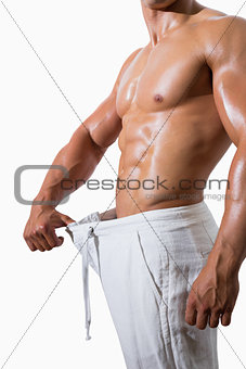 Mid section of a muscular man in an over sized pants