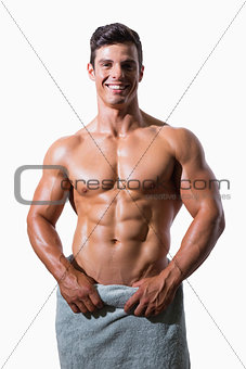 Smiling shirtless muscular man wrapped in white towel