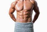 Mid section of a shirtless muscular man wrapped in white towel