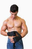 Shirtless muscular man binds bandage on his hand