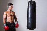 Shirtless muscular boxer looking at punching bag