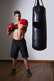 Muscular boxer with punching bag in gym