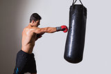 Shirtless muscular boxer with punching bag