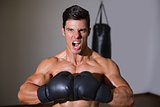 Muscular boxer shouting in health club