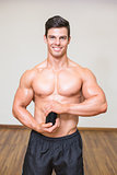 Body builder holding bottle with supplements in gym