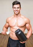 Body builder holding a scoop of protein mix in gym