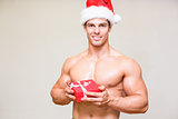 Shirtless macho man in santa hat holding gift