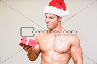Macho man in santa hat holding gift over white background