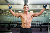 Shirtless bodybuilder with arms raised in gym
