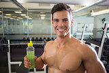 Sporty young man with energy drink in gym