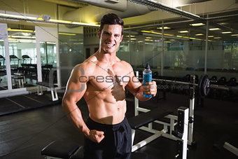 Muscular man holding energy drink in gym