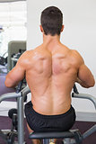 Muscular man working on abdominal machine at the gym