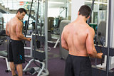 Shirtless muscular man using triceps pull down in gym