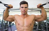 Shirtless muscular man using resistance band in gym