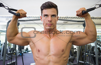 Shirtless muscular man using resistance band in gym