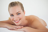 Beautiful blonde relaxing on massage table smiling at camera