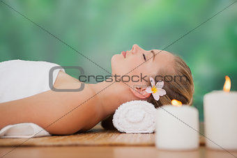 Peaceful blonde lying on bamboo mat with candles