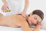 Attractive woman getting massage oil on her back