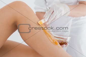 Therapist waxing woman's leg at spa center