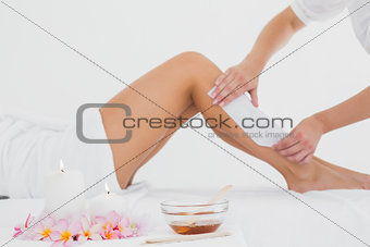 Therapist waxing woman\'s leg at spa center