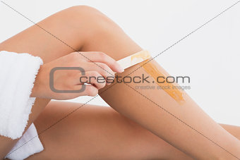 Side view of female applying hot wax on leg