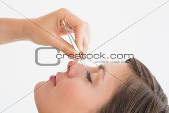 Close-up side view of hand plucking eyelashes