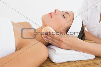 Hand cleaning woman's face with cotton swabs