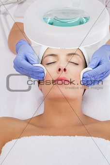 Hands cleaning woman's face with cotton swabs