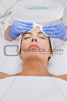 Hands cleaning woman's face with cotton swabs