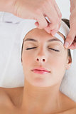 Hand waxing beautiful woman's eyebrow