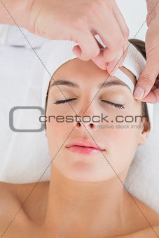 Hand waxing beautiful woman's eyebrow