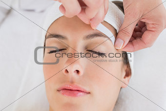 Hand waxing beautiful woman\'s eyebrow