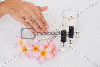 Hand in bowl along flowers and candle