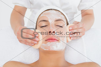 Hand cleaning woman's face with cotton swabs