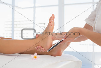 Side view of a young woman receiving pedicure treatment