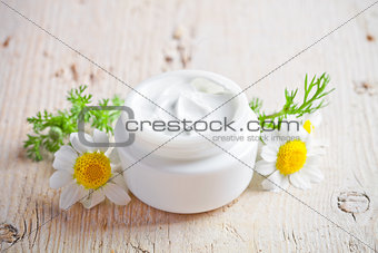 container with cream and chamomiles 
