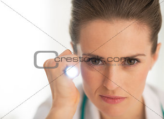 Portrait of doctor woman using flashlight