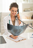 Smiling doctor woman with fluorography talking phone