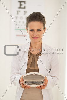 Doctor woman showing eyeglasses in front of snellen chart
