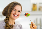 Portrait of smiling young housewife eating vegetables