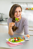 Young woman eating greek salad and watching tv