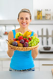 Smiling young woman showing fruits plate