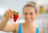 Closeup on happy young woman showing strawberry