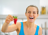 Smiling young woman showing strawberry