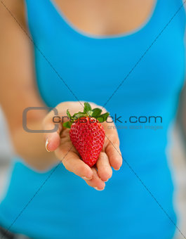 Closeup on young woman showing strawberry