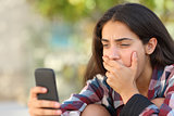 Worried teenager girl looking at her smart phone